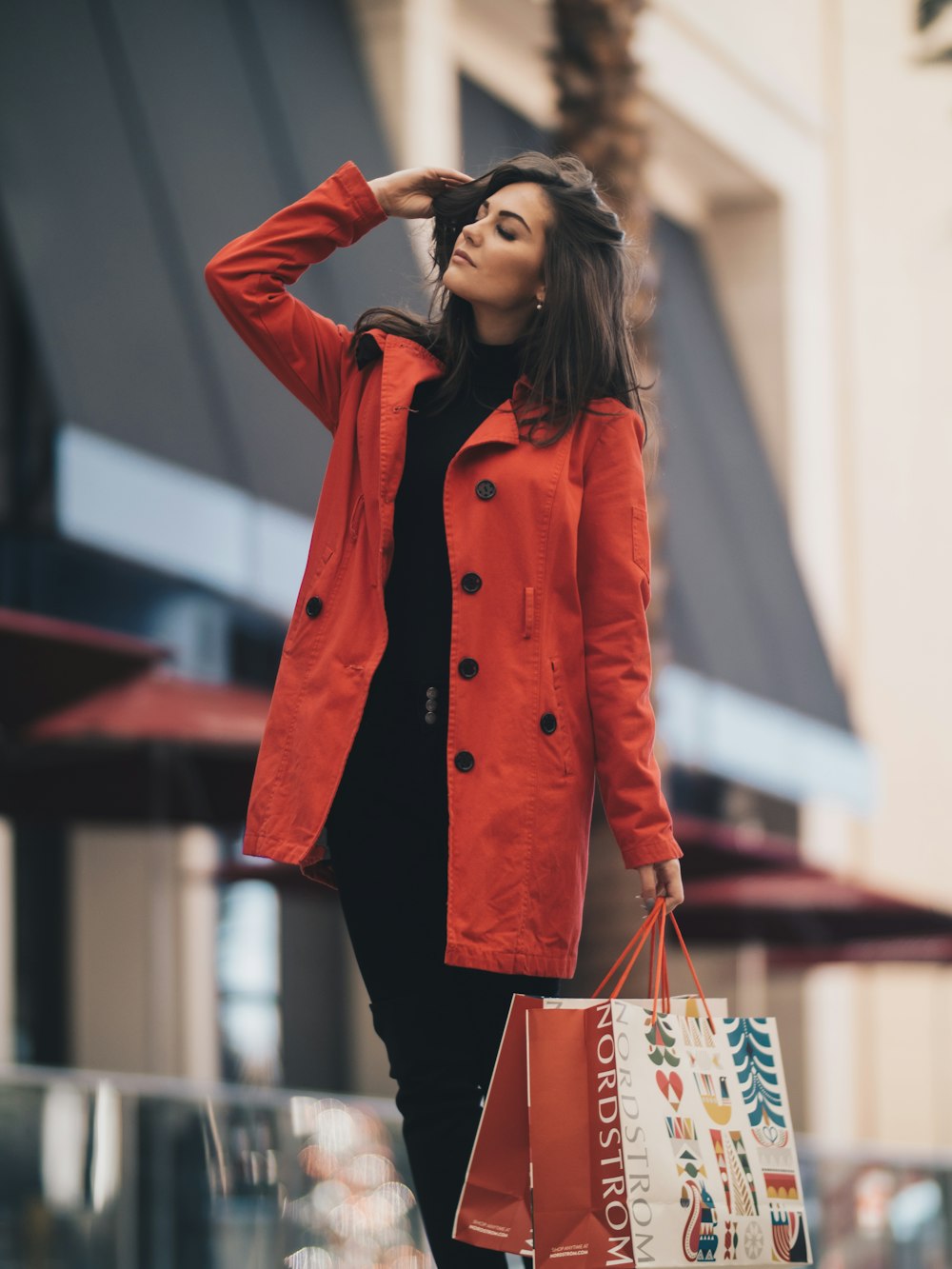 Woman in a red coat and ankle boots walking on a city street